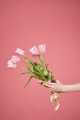 Bouquet of flowers in hands pink background gift womens day