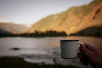 Mug of coffee in hand outdoors