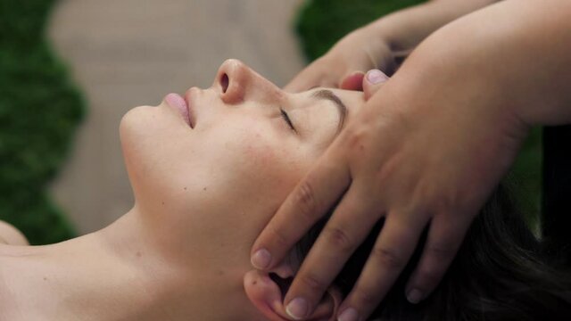 Beautiful young girl doing face and head massage in spa salon. Relax.
