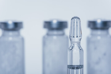Glass medical ampoule vial for injection. Medicine is liquid sodium chloride with of aqueous solution in ampulla. Close up. Bottles ampule multicolor.