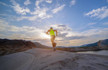 Triathlon runner running on sandy beach among mountain and blue sky background Fitness men practice...
