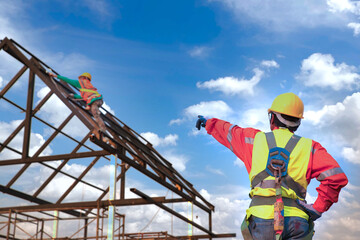 Engineer construction tecnician in a protective safety suit is pointing a team of workers on steel platform.Engineers are searching for and analyzing the unfinished construction project.