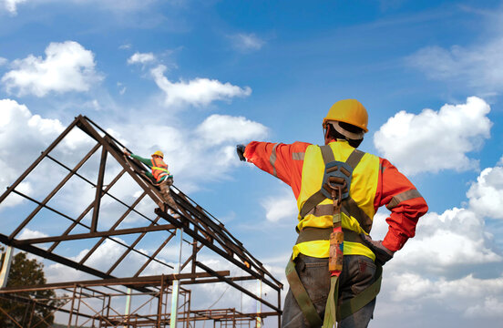 Engineer construction tecnician in a protective safety suit is pointing a team of workers on steel platform.Engineers are searching for and analyzing the unfinished construction project.