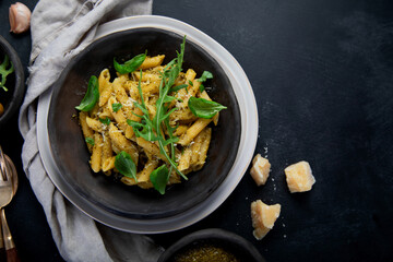 Pasta spaghetti with homemade pesto and fresh basil leaves on dark background. Italian cuisine concept.