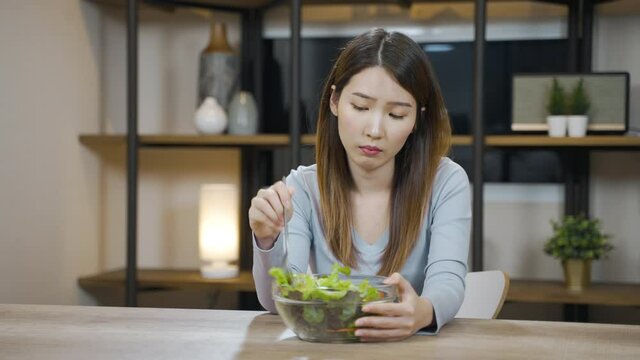 Asian woman bored to eat vegetable salad or healthy food for diet want to quit vegetarian