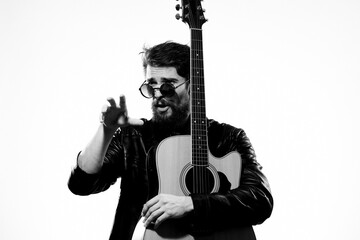 A man with a guitar black leather jacket light background performing a musician