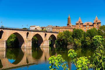 Montauban city on sunny day. Medieval bridge over the Tarn river. France - obrazy, fototapety, plakaty
