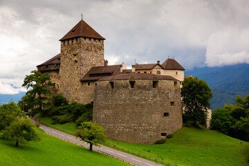 Fototapeta na wymiar Medieval architecture, Vaduz castle with Alps mountains in clouds on background