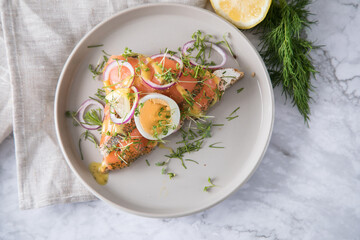 Gravlax Graved Lachs, ein roh gebeizter Fisch auf Toast Brot mit Hovmästarsås Senf Soße, Dill, Kresse, Ei, Zwiebel Ringe, Zitrone und Leinen Tuch auf hell Marmor Hintergrund