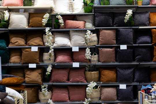 Many beautiful pillows in wooden shelf at Modern home textile store For Sale. Assorted throw pillows in textile shop for interior decor. Close Up shot of various types of pillows. Selective focus