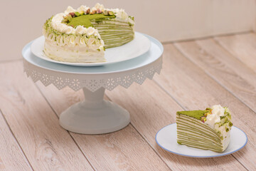 Matcha Mille Crepe Cake Presented On A Cake Holder With A Slice On A Plate.	