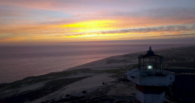 Sunset view of modern lighthouse at Cabo Falso, Cabo San Lucas overlooking the beach. Aerial approaching.