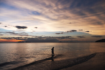 Silhouette image of a woman walking in the sea before sunset