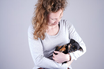 Obraz premium Part of a female, she lovingly holds a tiny sleeping Jack Russel Terrier puppy in her arms