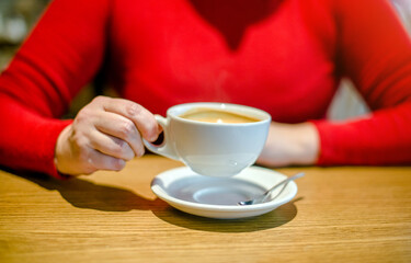A girl drinks coffee at a table in a cafe
