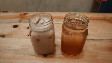 two glasses of iced tea and iced coffee on a wooden dining table