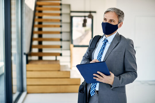 Real Estate Agent With Face Mask Takes Notes As He Walks Through The Property For Sale.