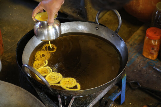 Man preparing jalebi in a frying pan