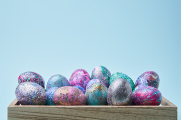 Colorful painted eggs with bright shiny gliter in wooden box