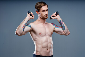 Fototapeta na wymiar sexy athletic men with dumbbells on gray background and biceps press tattoos