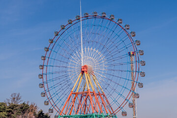 Colorful ferris wheel against blue sky with low wispy clouds.