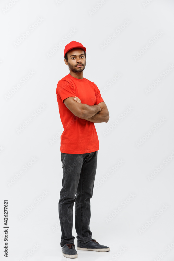 Wall mural Delivery Concept - Handsome African American delivery man crossed arms over isolated on Grey studio Background. Copy Space.