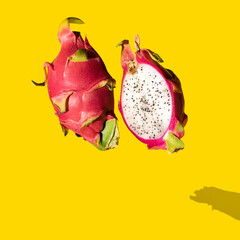 Delightful tropical yummy dragons fruit cut in half on bright yellow background. Floating above.