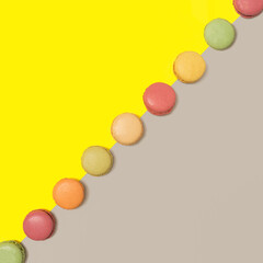 Lovely delicious and colorful macarons  aligned in diagonal against bright yellow and ultimate gray flat lay composition.