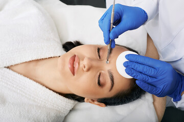 Cleansing face comedone spoon. Beautiful woman gets removal of comedones, blackheads, acne at a beauty clinic. View from above