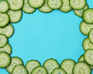 Fresh ripe cucumber slices on blue background, space for text