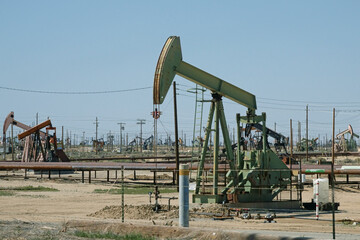 Fototapeta na wymiar Oil pumpjacks are shown in a large oil field during the day.