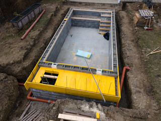 aerial drone shot of construction site from pool with formwork for concrete and finished brick wall...