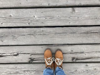 Background feet on a wooden sidewalk, abstraction, boots on a wooden walkway