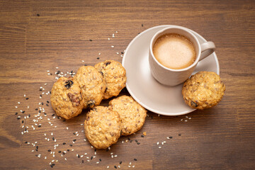 on the table oatmeal cookies with nuts, flax, sesame seeds and chocolate pieces with a cup of hot coffee