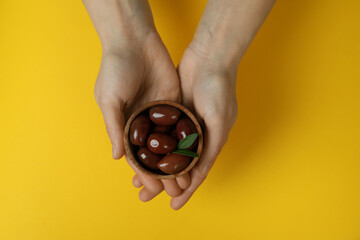 Female hands hold bowl of red olives