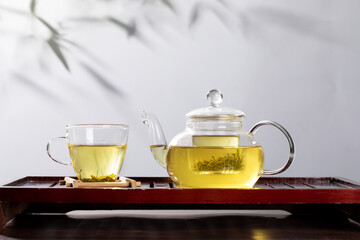 Closeup of a glass teapot and a cup with green tea on a tray on the tabl