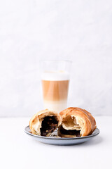 Croissant and coffee with milk on bright wooden background. Copy space.	