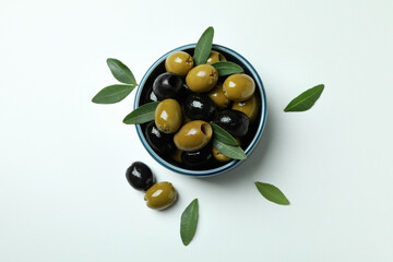Bowl of olives and leaves on white background, top view