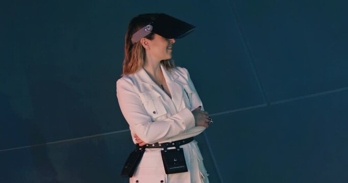 Slow Motion young woman in white trendy blazer closing her face by modern COVID 19 face shield. Smiling positively and looking around. Portrait of young cheerful playful stylish blond woman 4K footage