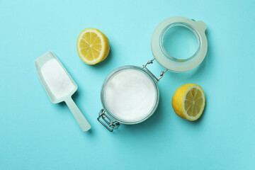 Scoop and jar with acid powder and halves of lemon on blue background