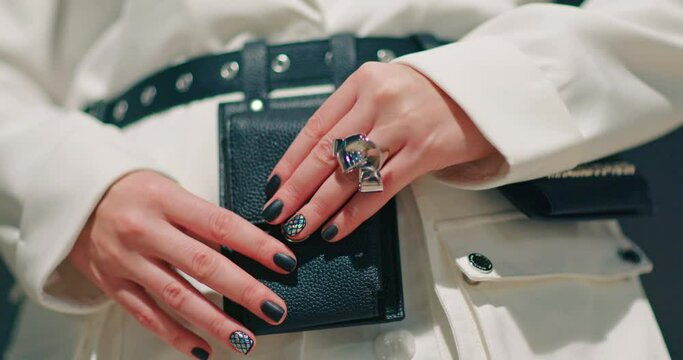 Slow motion stylish accessories business 4K commercial footage. Close up model in trendy white jacket with black manicure and metallic ring opening fashionable black belt with pockets and mini bags