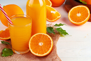Bottle of orange juice and fresh oranges on table