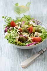 Salad with Green Olives, Tomatoes and Feta Cheese. Bright wooden background. 