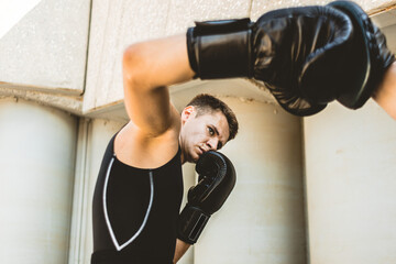 Two men exercising and fighting in outside. Boxer in gloves is training with a coach