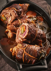 Dish of beef, bacon and pickle roulades in gravy seasoned with vegetables for a traditional regional German dinner. German traditional cuisine beef roulade with bacon and vegetables - 426288026