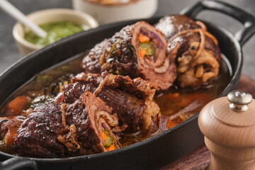 Dish of beef, bacon and pickle roulades in gravy seasoned with vegetables for a traditional regional German dinner. German traditional cuisine beef roulade with bacon and vegetables - 426288087