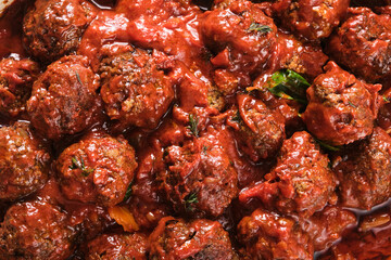 Macro shot of meat balls in tomato sauce with thyme.