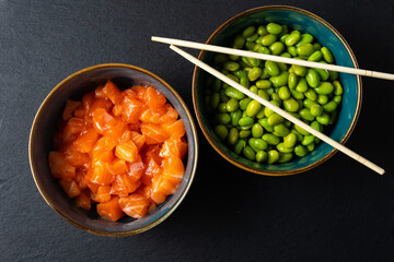 bowls of raw tuna and edamame with chopsticks on top. dark background. typical Asian ingredients