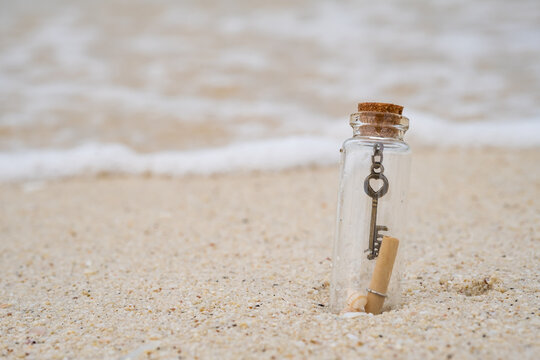 Letter and key in the glass bottle on the beach with wave in the sea. blur background with copy space for text.