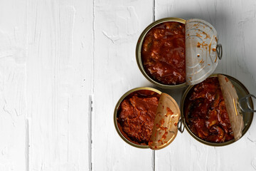 Top view of opened cans with fish conserves on wooden background